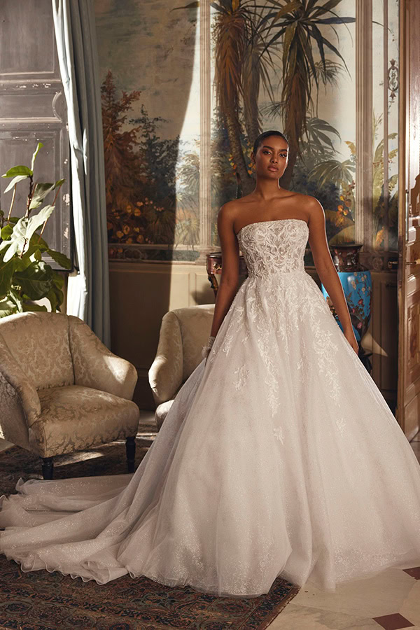 Eine elegant gekleidete Frau steht in einem weißen Brautkleid mit Spitzenmuster