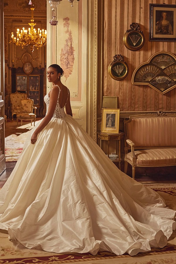 Eine elegant gekleidete Frau im weißen Brautkleid steht in einem prunkvollen Raum