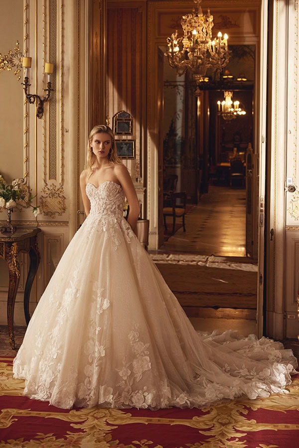 Junge Frau mit ernstem Blick trägt ein elegantes cremefarbenes Brautkleid im Prunksaal