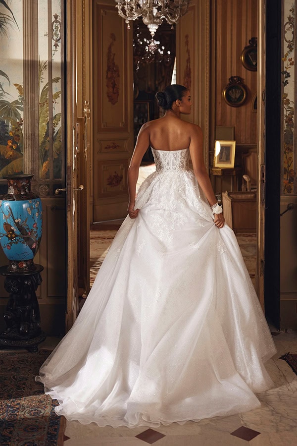 Eine elegant gekleidete Frau in weißem Brautkleid steht in einem prunkvollen Raum