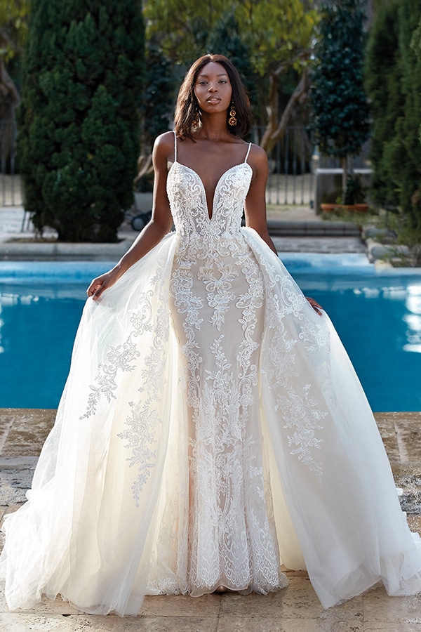 Eine elegant gekleidete Frau im weißen Brautkleid steht an einem blauen Pool