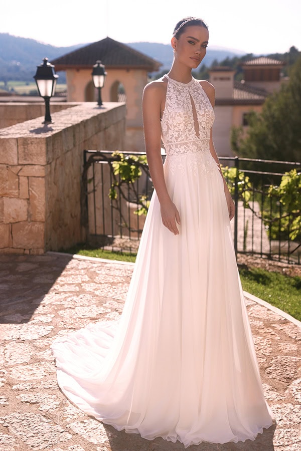 Eine junge Frau mit elegantem Ausdruck trägt ein weißes Spitzenkleid im Sonnenlicht