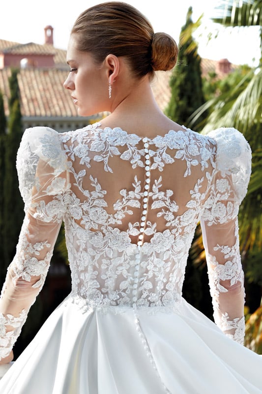 Frau mit strengem Dutt in elegantem Brautkleid mit floraler Spitze und Knopfleiste
