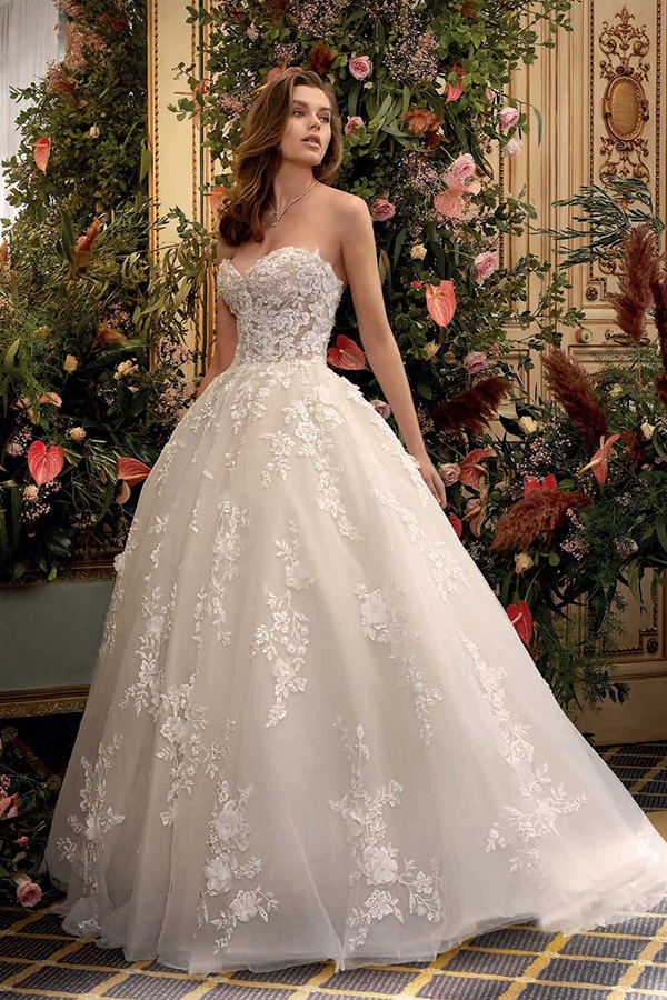 Eine Frau mit langen braunen Haaren trägt ein cremefarbenes Brautkleid mit Spitze