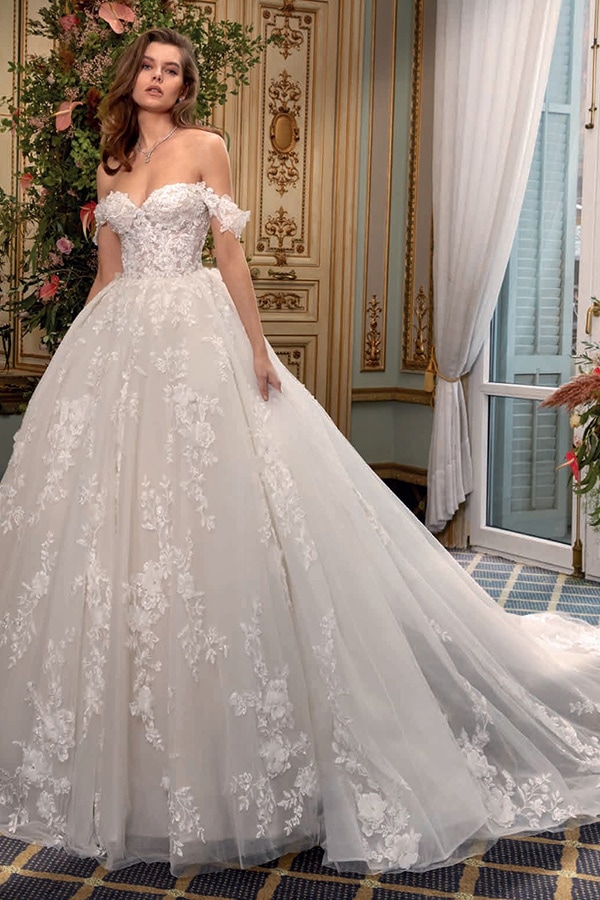 Junge Frau mit offenem Haar steht im weißen Brautkleid und schaut nachdenklich