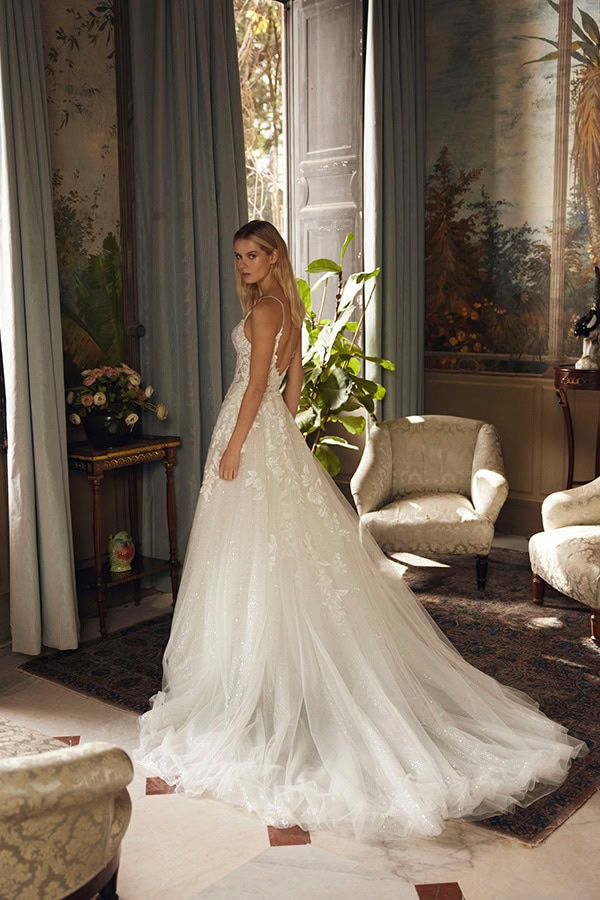 Junge Frau mit ernstem Blick in weißem Brautkleid im eleganten Raum mit Pflanzen