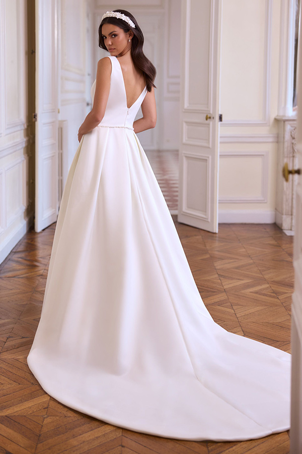 Eine brünette Frau im weißen Brautkleid blickt ernsthaft über die Schulter