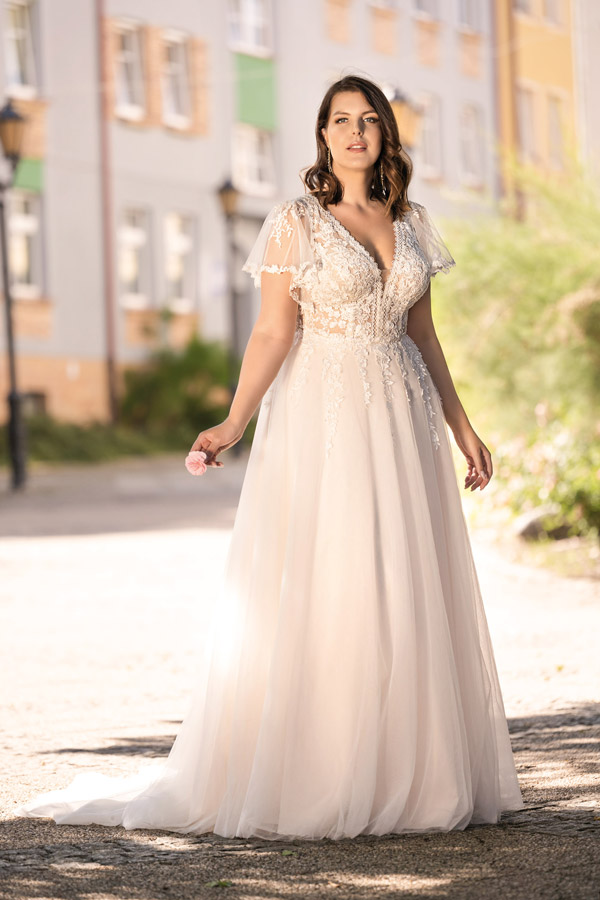 Junge Frau im cremeweißen Brautkleid mit Spitze und entspanntem Gesichtsausdruck