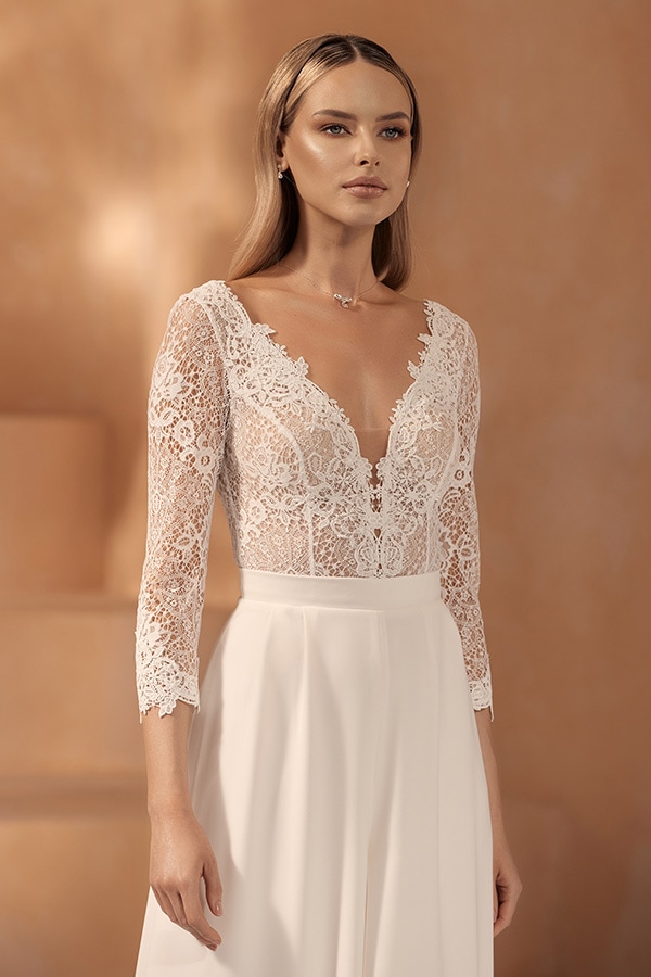 Junge Frau mit neutralem Blick trägt ein elegantes, weißes Brautkleid aus Spitze