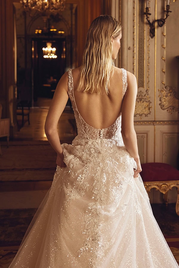 Eine blonde Frau mit glattem Haar trägt ein elegantes cremefarbenes Glitzerkleid