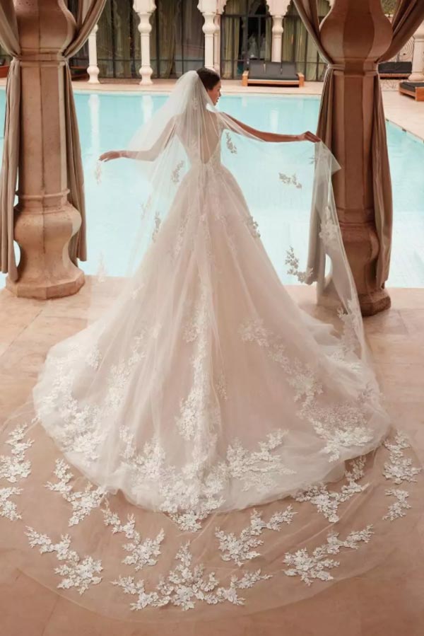 Eine Braut in einem eleganten weißen Kleid mit Spitze posiert an einem Pool