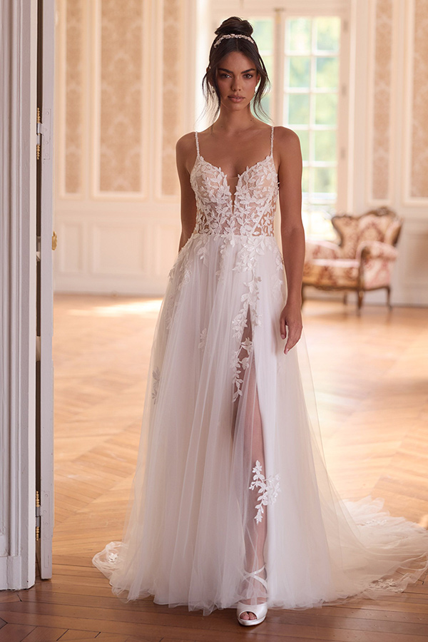 Eine junge Frau mit ernster Miene trägt ein weißes Spitzenkleid mit transparentem Oberteil