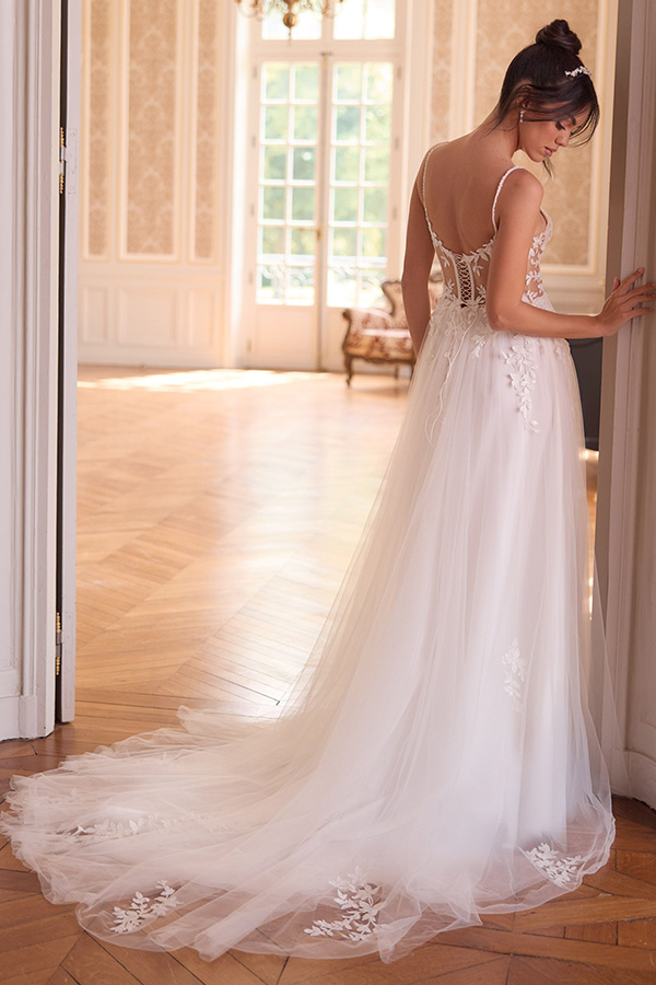 Eine Frau mit locker hochgesteckten Haaren trägt ein elegantes weißes Brautkleid