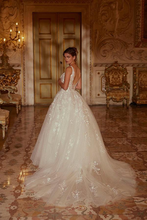 Junge Frau mit elegantem Ausdruck in einem weißen Brautkleid in einem prunkvollen Raum