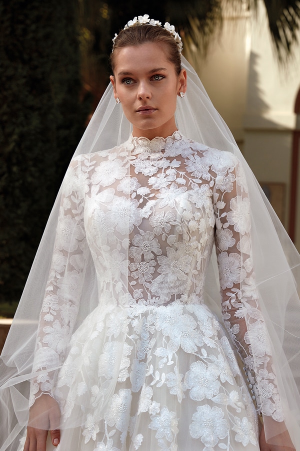 Junge Frau mit neutralem Ausdruck in Spitzenhochzeitskleid und zartem Schleier