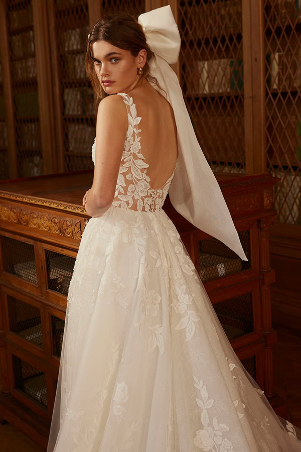 Junge Frau mit ernster Miene im cremeweißen Brautkleid und großem Schleifenhaarband