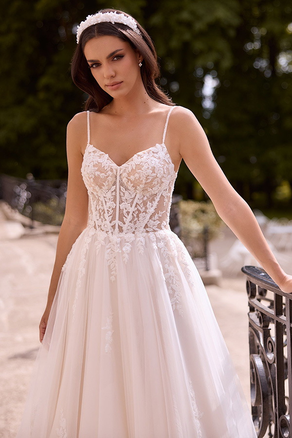 Junge Frau mit langen dunklen Haaren in einem eleganten Spitzenbrautkleid draußen