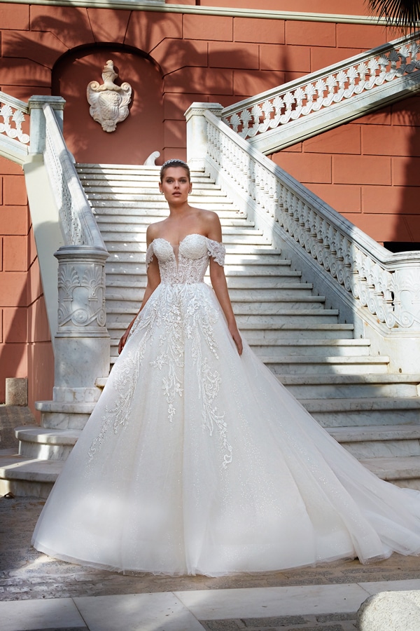 Junge Frau mit ernstem Blick in weißem Brautkleid vor eleganter Marmortreppe