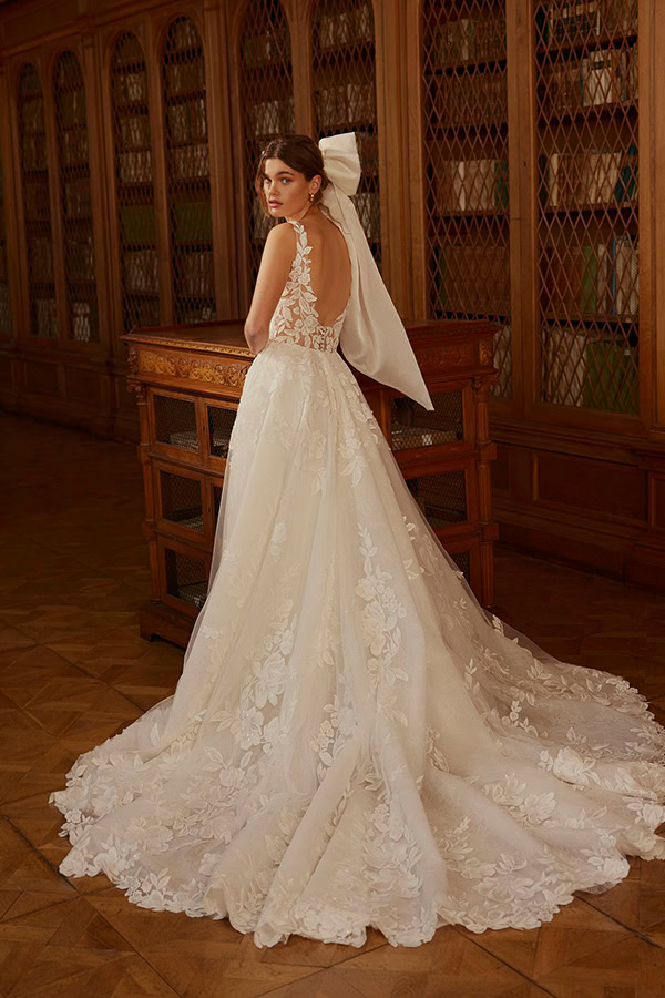 Frau mit elegantem weißen Brautkleid und großem Rückenausschnitt blickt ernst zurück