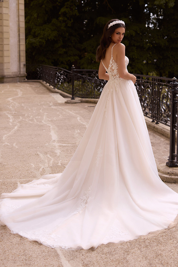 Eine junge Frau mit langem braunen Haar im cremefarbenen Brautkleid schaut zurück