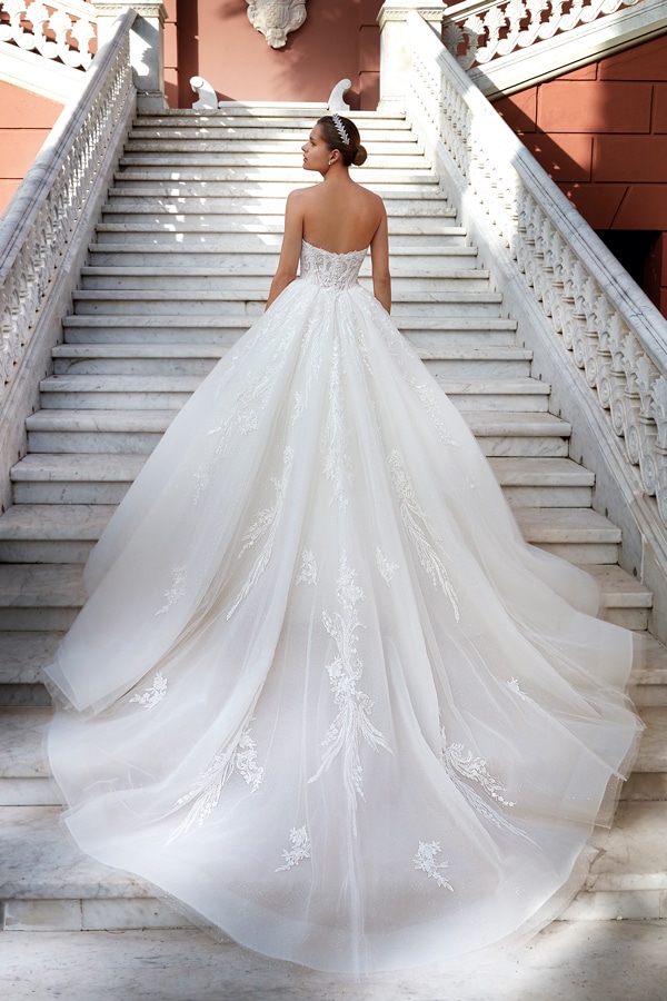 Eine Frau in einem weißen Brautkleid mit langer Schleppe steht auf Marmortreppen