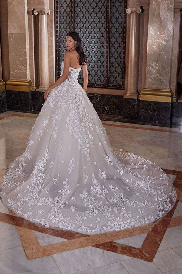 Eine Braut schaut elegant über die Schulter, ihr weißes Kleid mit Blumenmuster glänzt