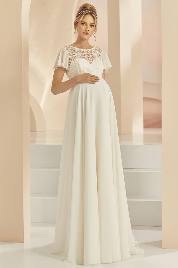 Schwangere Frau mit sanftem Lächeln in weißem Kleid mit Spitze und goldener Tiara