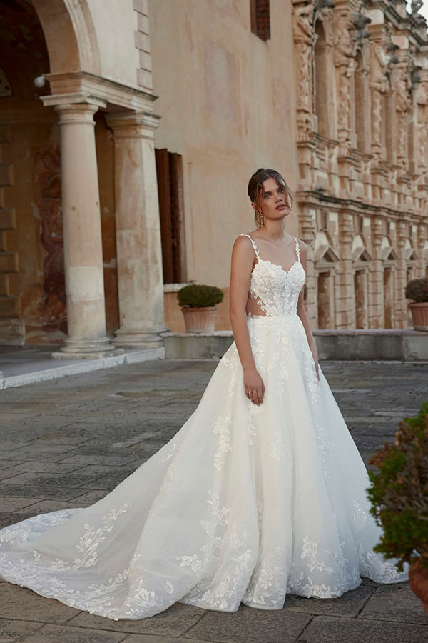 Eine junge Frau mit ernstem Gesichtsausdruck trägt ein aufwendig besticktes weißes Brautkleid