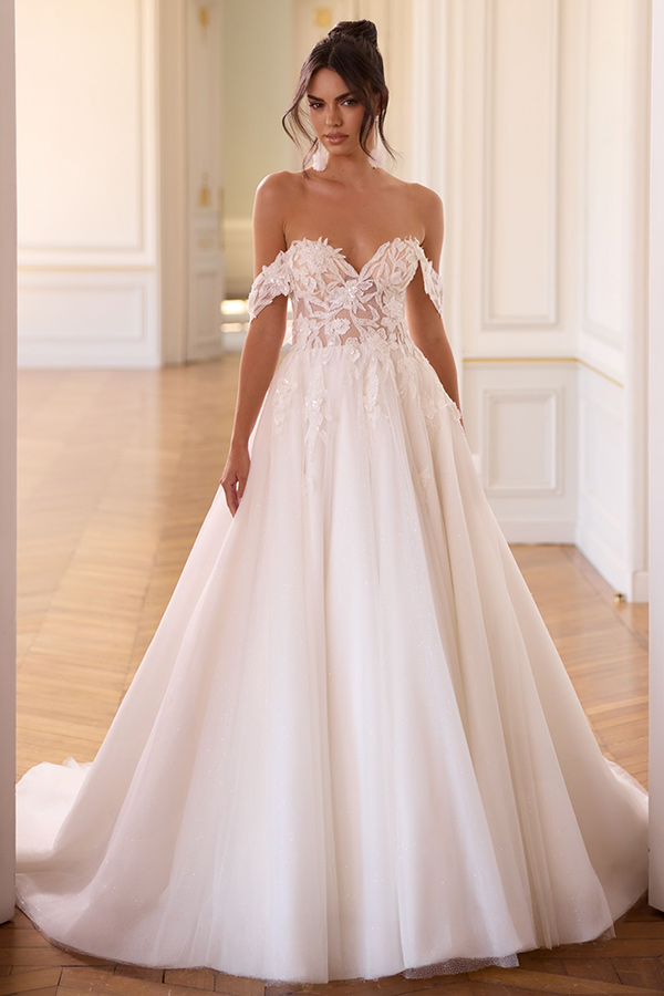 Junge Frau mit ernstem Blick trägt ein elfenbeinfarbenes Kleid mit floralen Details