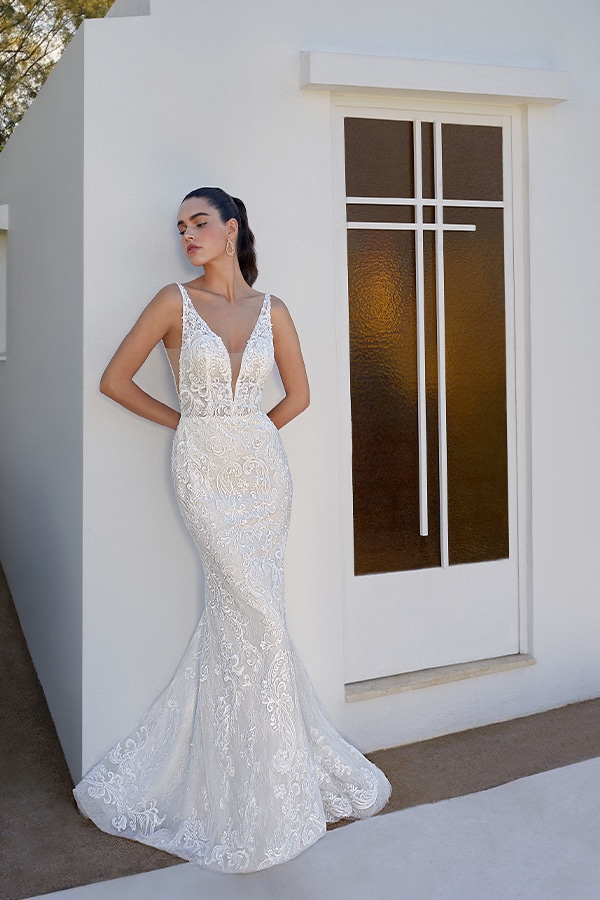 Eine elegante Frau posiert nachdenklich in einem verzierten Spitzenkleid in Weiß