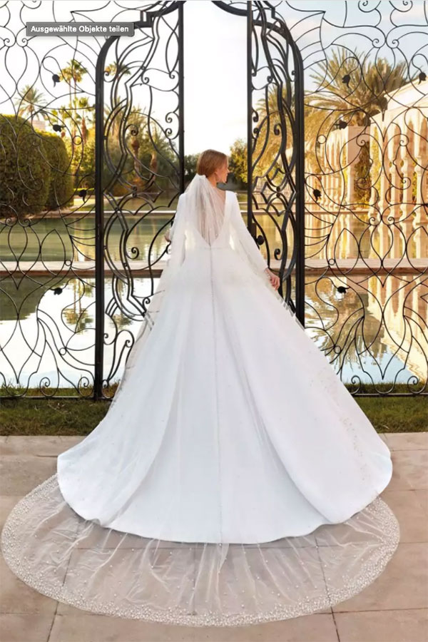 Eine Frau in einem eleganten weißen Brautkleid steht vor einem kunstvollen Tor