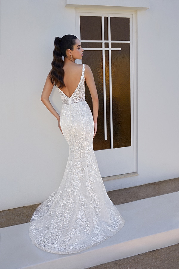 Eine Frau mit langen dunklen Haaren trägt ein figurbetontes weißes Spitzenkleid