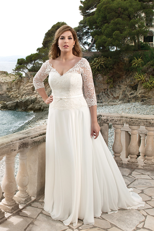 Junge Frau mit entspanntem Blick trägt ein elegantes weißes Hochzeitskleid aus Spitze