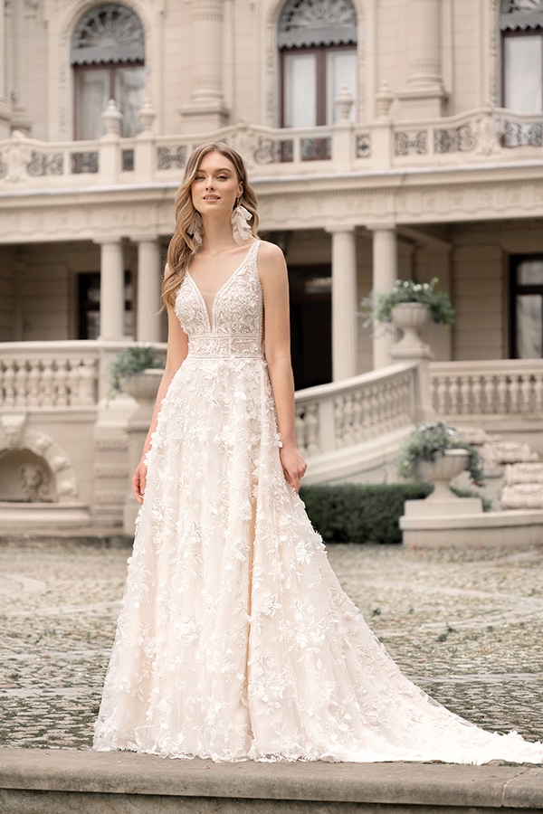 Eine lächelnde junge Frau im cremefarbenen Brautkleid mit floralen Verzierungen