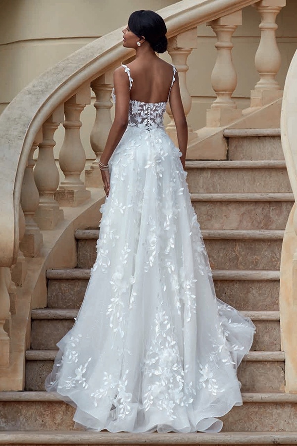 Eine Frau mit dunkler Haut steht elegant auf einer Steintreppe in weißem Spitzenkleid