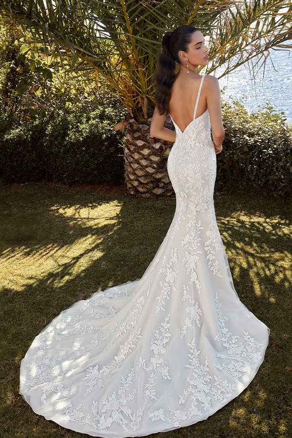 Eine dunkelhaarige Frau steht im Freien und trägt ein elegantes weißes Spitzenkleid