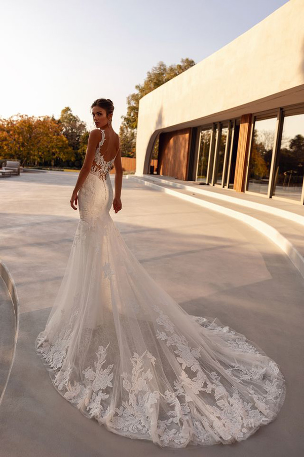 Braunhaarige Frau im eleganten weißen Brautkleid mit ausdrucksvollem Spitzenmuster