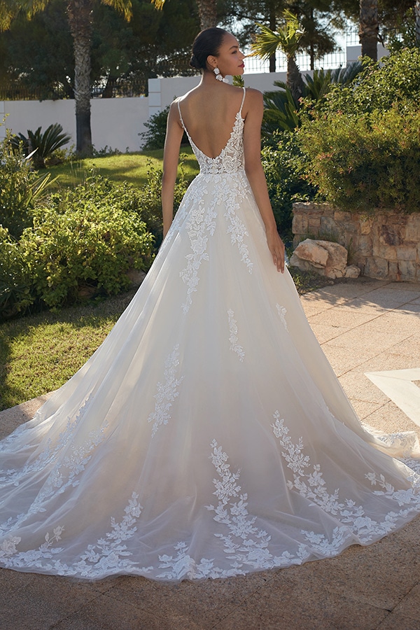 Eine Frau mit elegantem weißem Spitzenkleid steht draußen und wirkt zufrieden