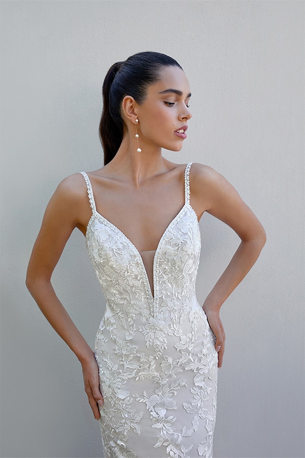 Eine junge Frau mit ernster Miene trägt ein elegantes, weißes Spitzenkleid