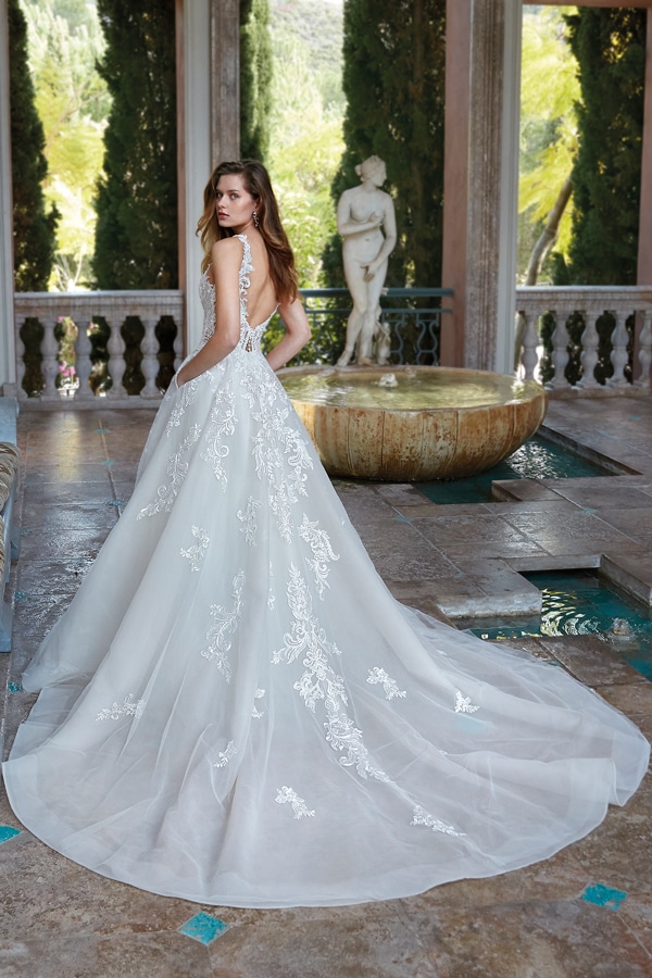 Eine junge Frau im eleganten weißen Brautkleid blickt verträumt über die Schulter