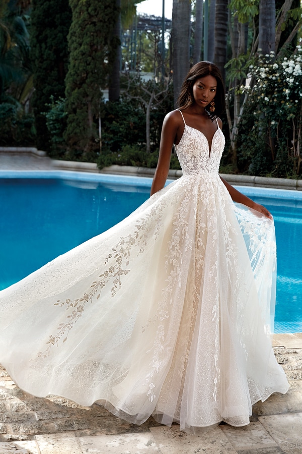 Eine Frau mit ernstem Blick trägt ein cremefarbenes Spitzenkleid am Pool