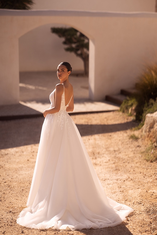 Eine Frau mit elegantem weißen Brautkleid blickt über die Schulter und lächelt sanft