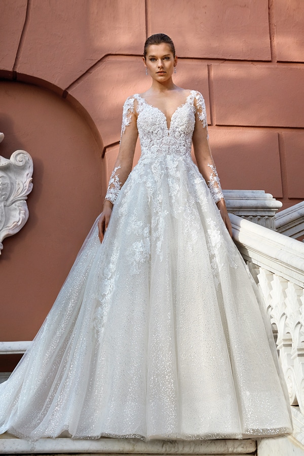 Junge Frau mit ernster Miene in weißem, glitzerndem Brautkleid auf Treppe