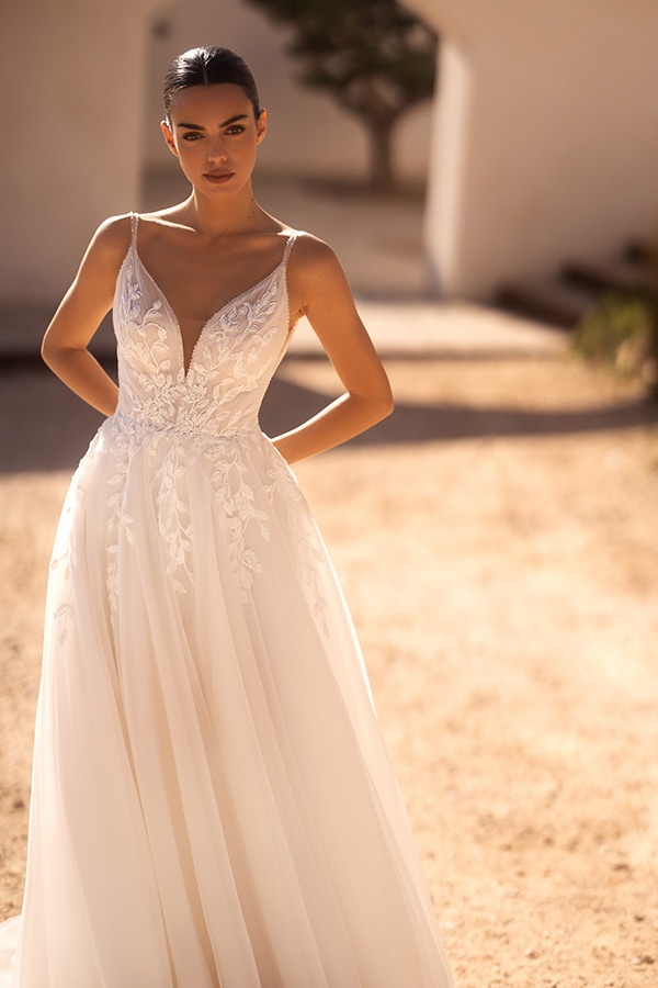 Dunkelhaarige Frau in elegantem elfenbeinfarbenem Brautkleid mit floralen Details