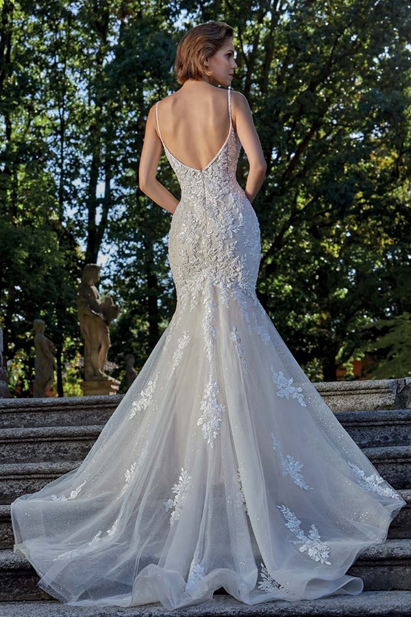 Eine Frau mit kurzem braunem Haar steht auf Treppen in einem eleganten weißen Brautkleid