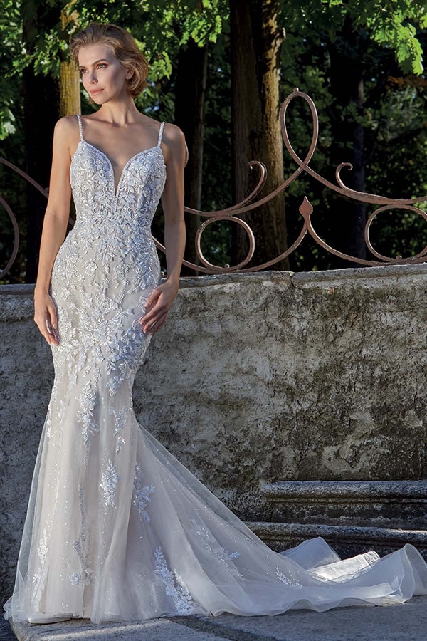 Eine blonde Frau mit elegantem Ausdruck trägt ein eng anliegendes weißes Brautkleid