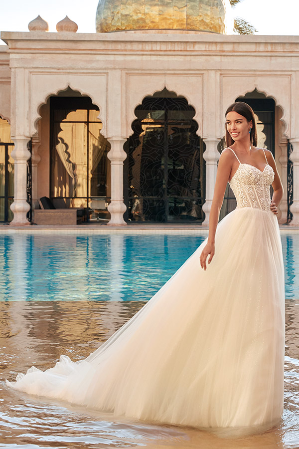 Eine lächelnde Frau im weißen Brautkleid steht vor einem prächtigen Gebäude mit Kuppel