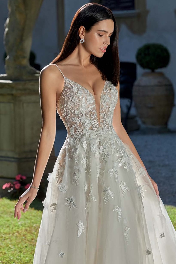 Brünette Frau im eleganten Brautkleid mit Spitze und tiefem Ausschnitt wirkt nachdenklich