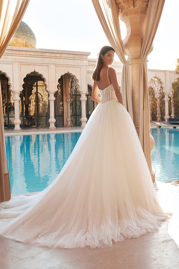 Frau mit langem weißen Brautkleid lächelt entspannt an elegantem Pool