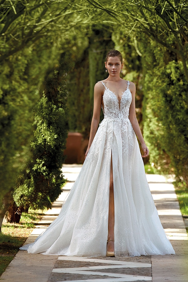 Eine junge Frau mit ernstem Blick trägt ein elegantes weißes Brautkleid mit Spitze